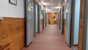 A hotel corridor with wooden paneling on the left, a reception desk at the end, and doors on both sides. - Kimstay9 (Seoul)