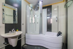 A modern bathroom with a white sink, a glass-enclosed shower, and a white bathtub. - Fabhotel Panchvati Residency Andheri West (Mumbai)