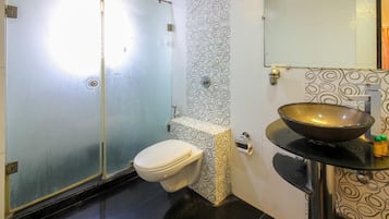 A bathroom with a toilet, a sink with a bowl, and a shower.
