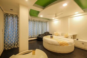 A modern bedroom with a curved bed, a ceiling fan, and a window with patterned curtains. - Fabhotel Panchvati Residency Andheri West (Mumbai)