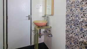 Casa de banho com lavatório de vidro, espelho e parede revestida com padrão pontilhado.