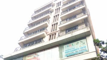 A multi-story building with balconies and several commercial signs on the ground floor.