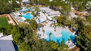 Eine Vogelperspektive auf ein Resort mit mehreren Schwimmbecken, einem großen Gebäude und umgebender Bepflanzung.
