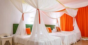 Habitación de hotel con dos camas, ambas cubiertas con sábanas blancas y dos dosel.
