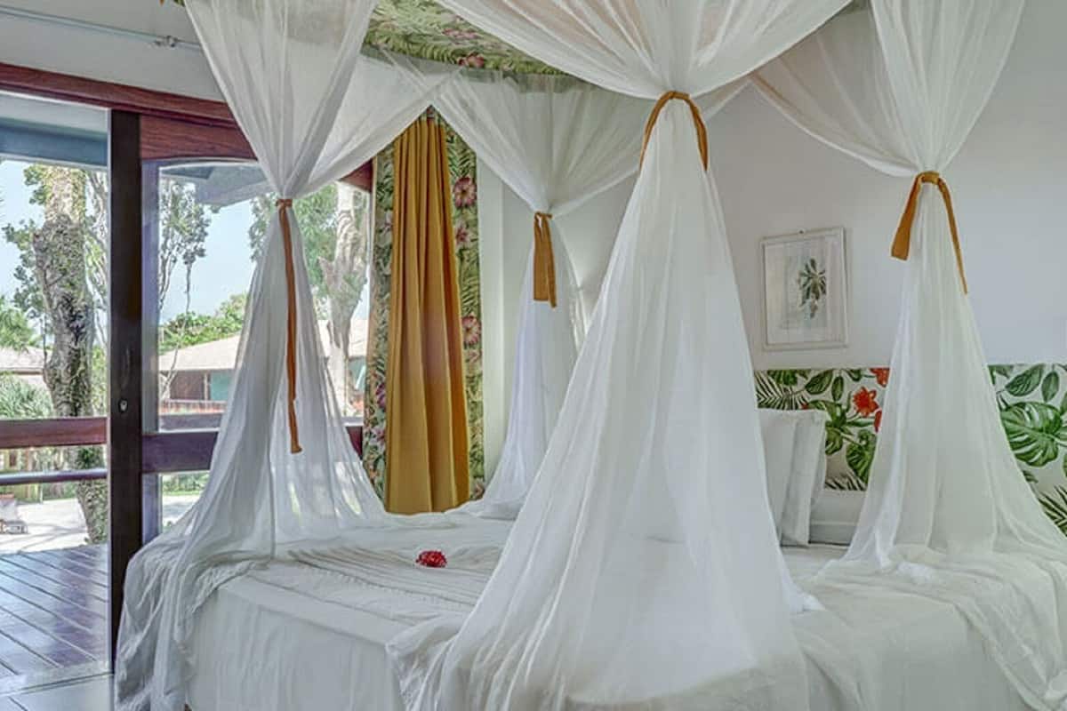 Ein Zimmer mit einem Himmelbett, einem Holztisch und Blick ins Freie.