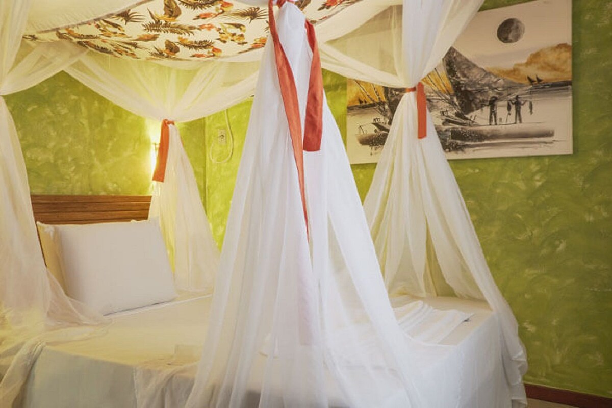A bed with a canopy and a painting on the wall.