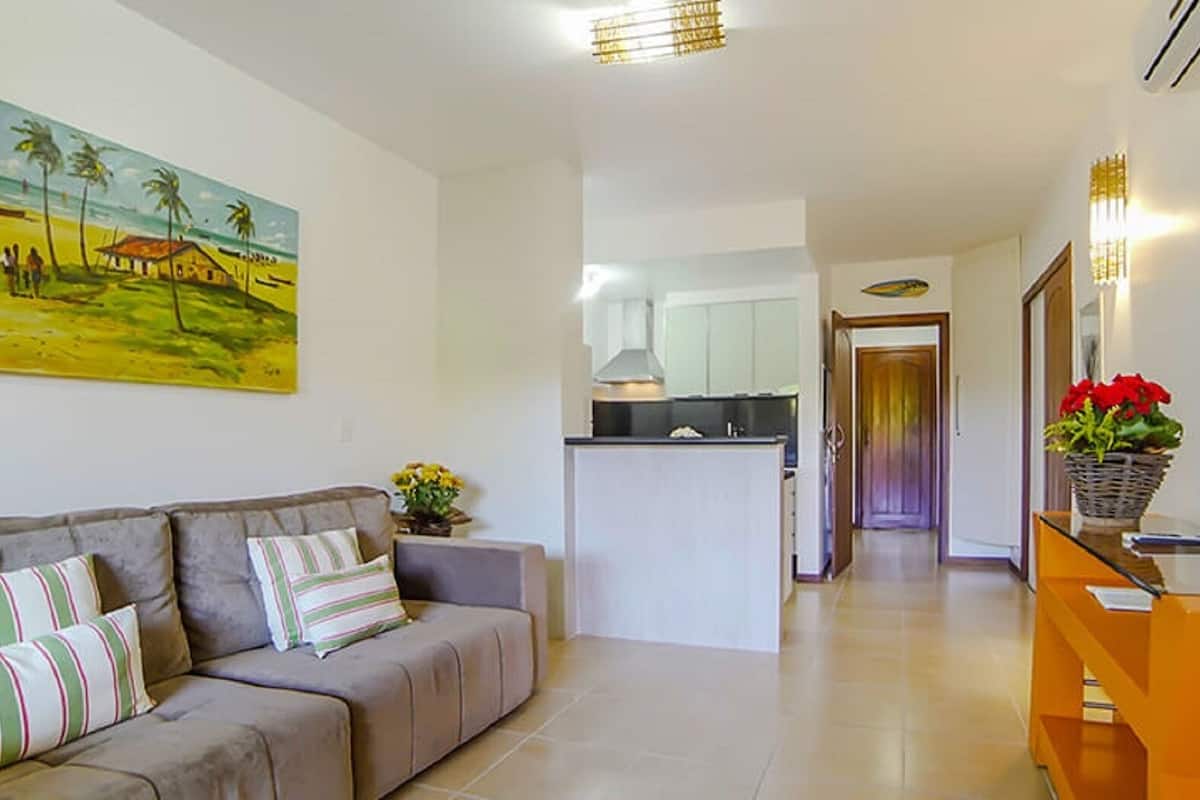 Ein Wohnzimmer mit Sofa, einem Gemälde, einem Fernseher und einer Küche im Hintergrund.