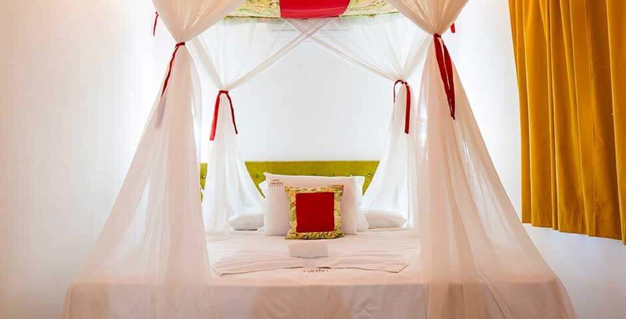 A bed with a canopy, a green headboard, and a red pillow.