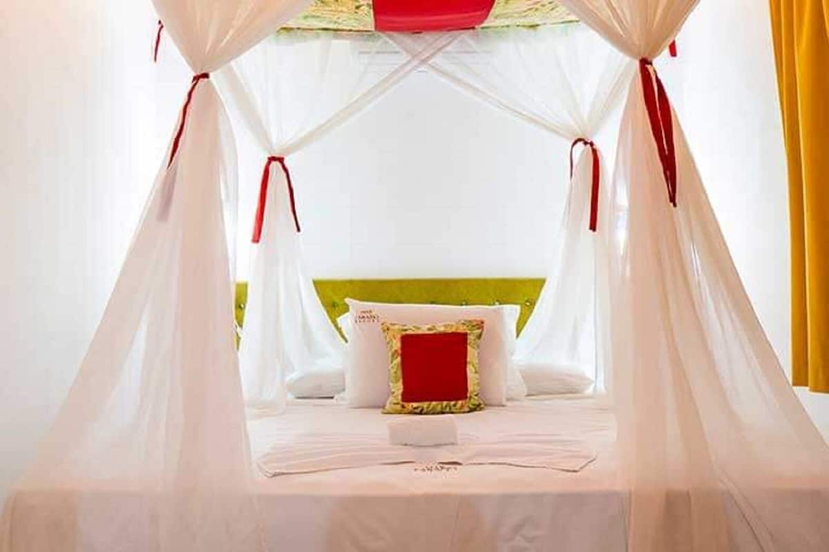 Ein Bett mit Baldachin, einem grünen Kopfteil und einem roten Kissen.