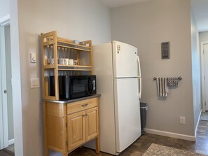 Enjoy cooking in this kitchen with a refrigerator, microwave, and trash bin.