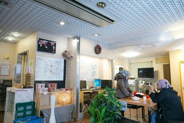 A restaurant with a map on the wall, a television, and a counter with a cash register. - Hotel Mikado (Osaka)