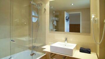 A modern bathroom with a glass-enclosed shower, a white sink, and a large mirror above the vanity.