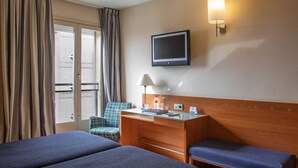 A hotel room with a bed, a desk, a chair, a television, and a window with curtains. - Hotel J. Balmes Vic (Vic)