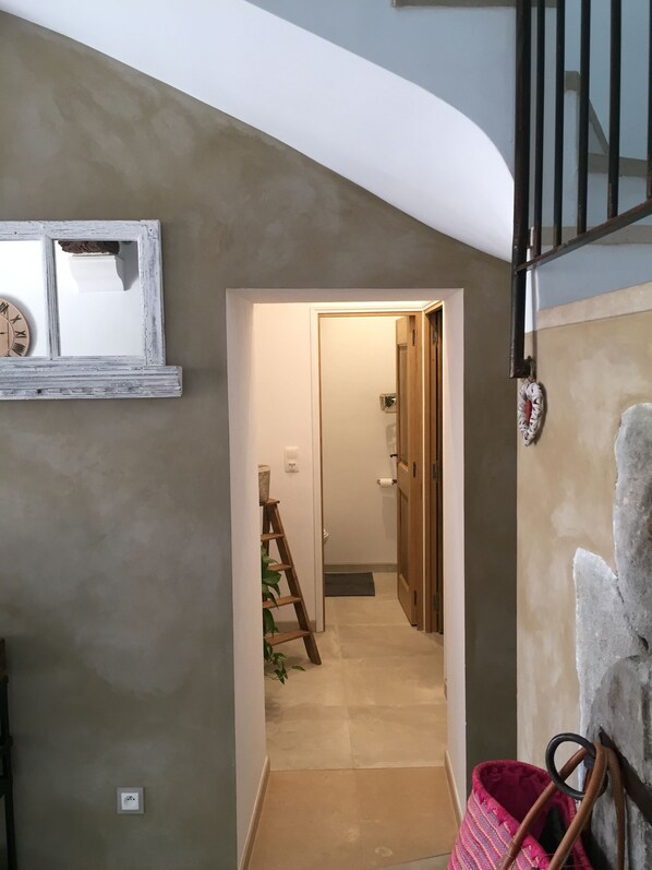 A hallway with a wooden ladder, a door leading to a bathroom, and a staircase.