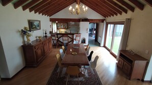 A spacious dining area with a wooden table and chairs, a chandelier, and a view to the outside. - House with breathtaking view of the mountains (Adast)