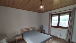 A bedroom with a wooden bed, a nightstand, a chair, a dresser, and a window with curtains. - House with breathtaking view of the mountains (Adast)
