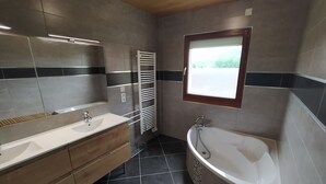 A modern bathroom with a large bathtub, a double sink vanity, and a towel rack. - House with breathtaking view of the mountains (Adast)