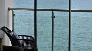 Un balcón con vistas al mar y un velero a lo lejos.