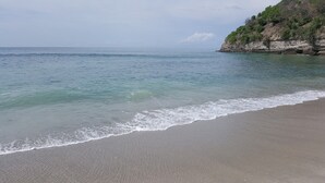 Una playa con agua cristalina y un acantilado rocoso.