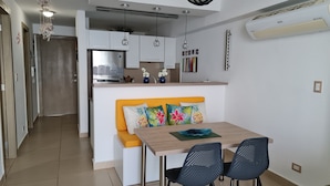 Una cocina moderna con armarios blancos, horno empotrado y refrigerador de acero inoxidable.