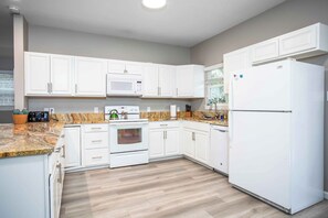 A modern kitchen with white cabinets, a built-in microwave, an oven, and a refrigerator.