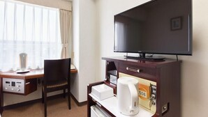 A hotel room with a desk, chair, television, coffee maker, and a window with curtains. - City Hotel Seiunso (Sakai)