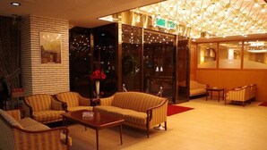 A lobby with striped sofas, a wooden coffee table, and a chandelier. - City Hotel Seiunso (Sakai)