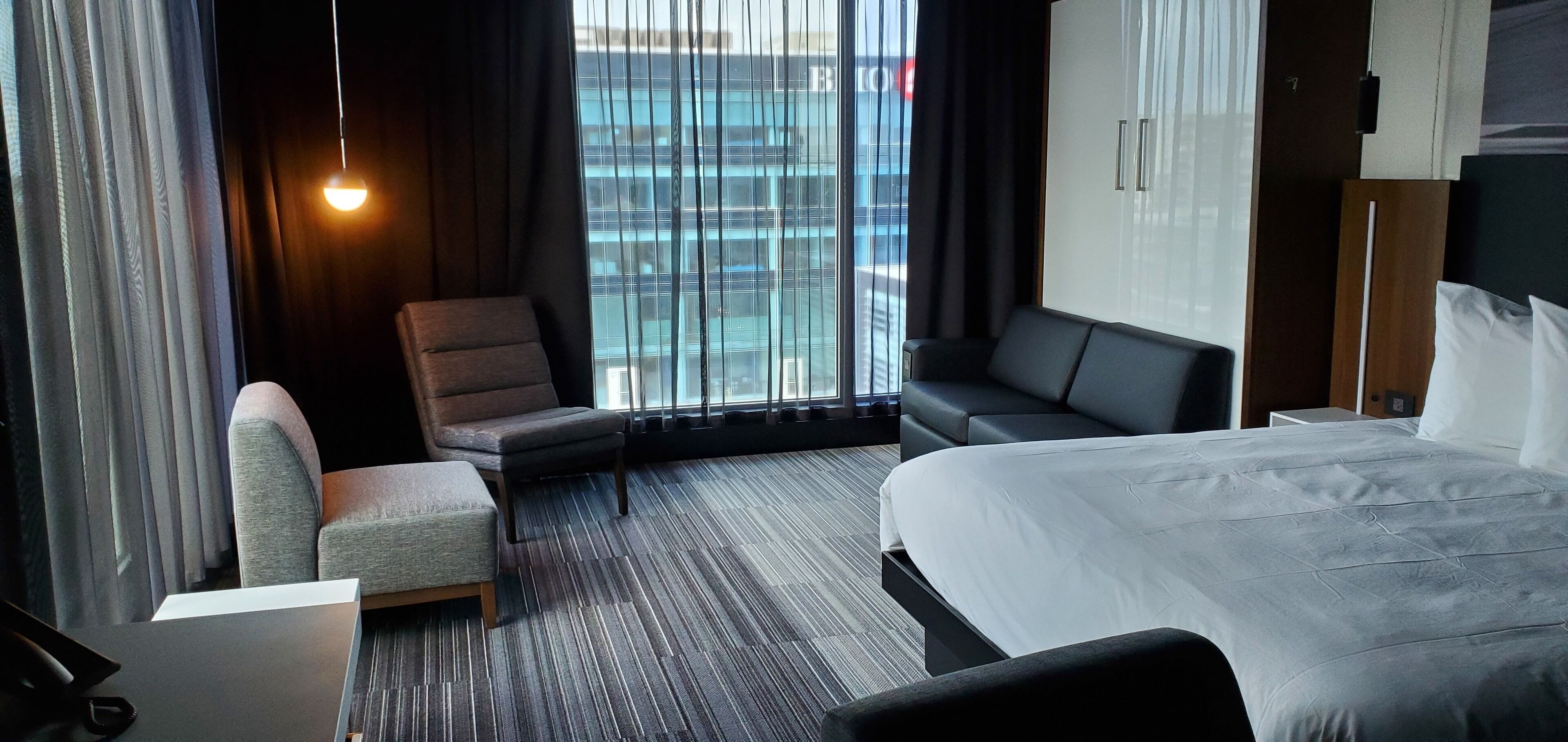 Una habitación de hotel con una cama, un sofá, una silla y un escritorio.