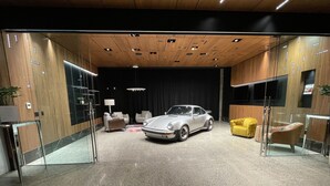 Um interior moderno com um carro clássico, lambris de madeira e mobiliário contemporâneo.