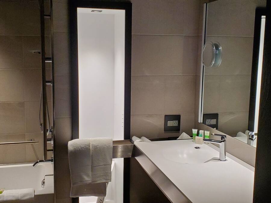 A modern bathroom with a large mirror, a bathtub, and a vanity with a sink.