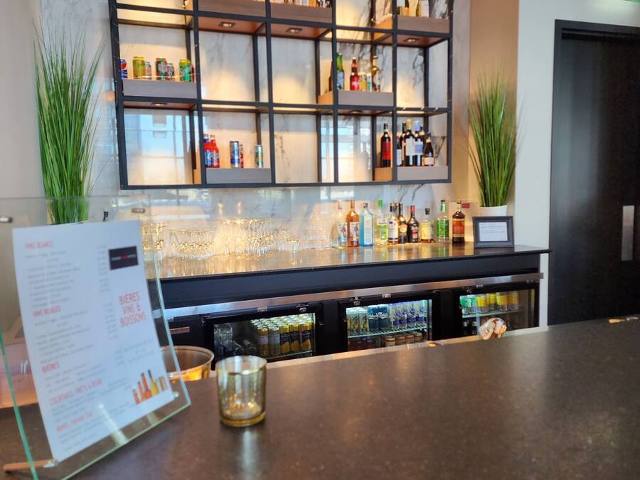 Un espace bar avec des étagères remplies de bouteilles et de verres, ainsi qu’un présentoir pour les menus.