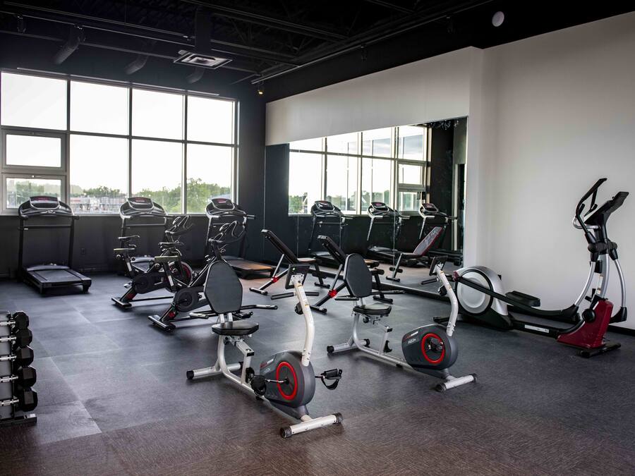A gym with various exercise equipment, large windows, and a view of the outdoors.