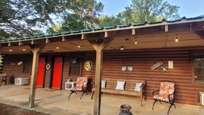 Eine rustikale Holzhütte mit einer Laube, roten Türen und Sitzgelegenheiten im Freien.