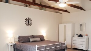 A bedroom with a bed, bedside tables, a wardrobe, a ceiling fan, and a compass wall decoration.