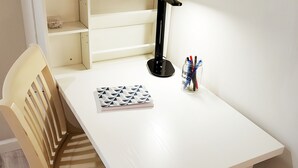A white desk with a chair, a desk lamp, and a container with pens and pencils.