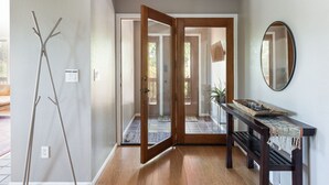 Un pasillo con un banco de madera, un espejo y una puerta que da a otra habitación.