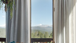 Un sofá de cuero con vistas a montañas a través de una ventana con cortinas.