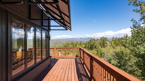 Una terraza de madera con puertas de vidrio que dan a una vista de la montaña.