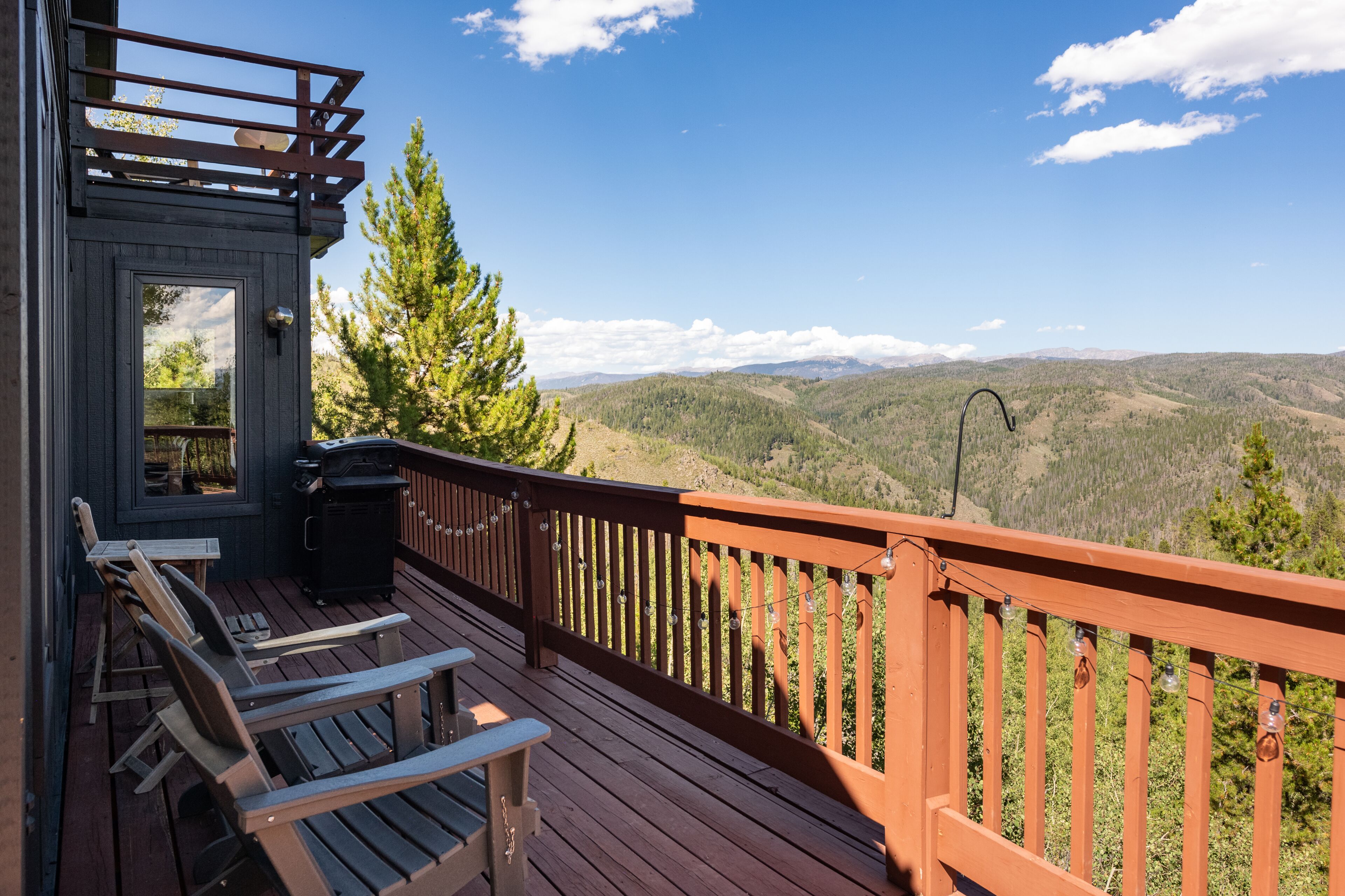 A wooden deck with outdoor seating and a view of a mountainous landscape.