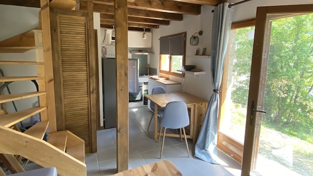A wooden interior with a spiral staircase, a dining area, and a kitchen.