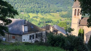 A rural village with a church tower, houses, and a mountainous backdrop.
