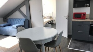 Un espacio habitable compacto con un entrepiso para dormir, una zona de comedor y una kitchenette.