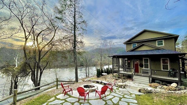 Une maison au bord du lac, dotée d’une terrasse en pierre, de chaises rouges et d’un belvédère.
