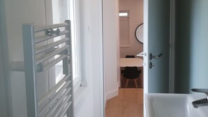 Un baño moderno con lavamanos, espejo y puerta que da a un dormitorio.