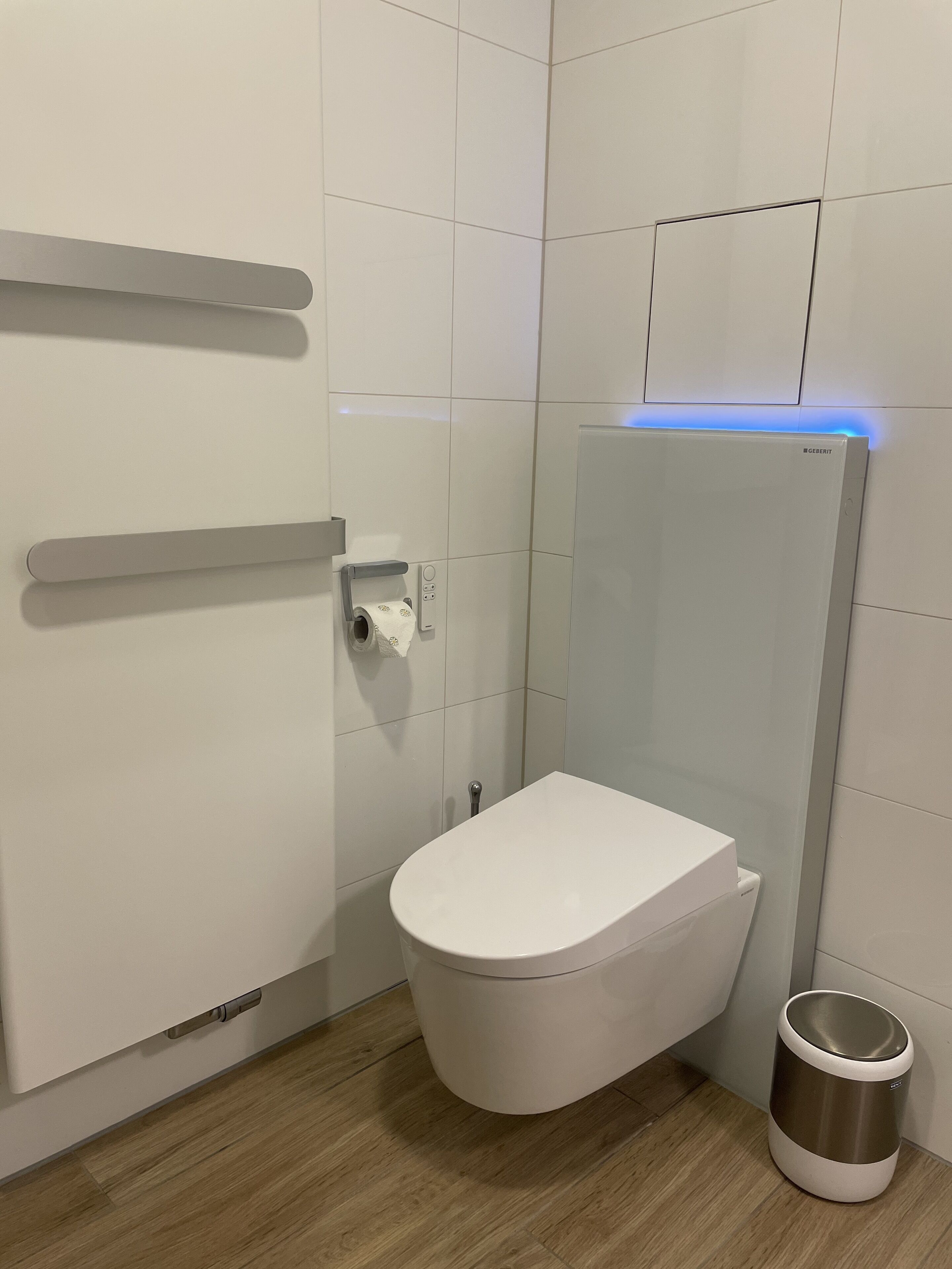 A modern bathroom with a white toilet, a glass shower enclosure, and a toilet paper holder.