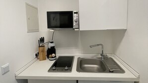 Una kitchenette compacta con microondas, pileta y una pequeña mesada.