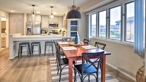 A modern kitchen with white cabinets, a central island, and a dining area with a wooden table and chairs.