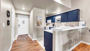 Una cucina moderna con mobili blu scuro, un piano di lavoro bianco e un forno a microonde.