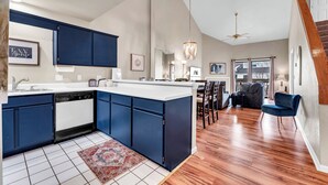 Una cucina moderna con mobili blu, un piano di lavoro bianco e un pavimento in legno.