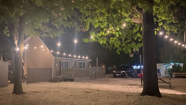 Ein kleines Gebäude mit Veranda, umgeben von Bäumen und Lichterketten.